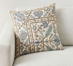 a white couch with a blue and gold pillow on it's backrests