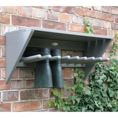 there are two metal bells on the wall next to a brick building with ivy growing around it