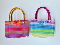 two colorful handbags with bows on them are lined up against a white background, one is brightly colored and the other is multicolored