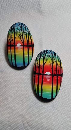 two buttons with trees painted on them sitting next to each other in front of a white background