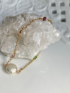 "Introducing a beautiful gem laden 14k gold filled chain with a blue sapphire, pink quartz, orange topaz, peridot, and amethyst.  Focal bead a highly iridescent, 12mm coin pearl.  The S clasp makes this bracelet adjustable from 7 1/2 to 7 3/4\". However this can be customer sized.  14k gold filled lobster clasp is new and like all the metal components manufactured in the USA to assure quality and meet EU Standards of gold quality. Handmade at my bench in Boston." 14k Gold Filled Jewelry With Gemstone Accents, Elegant 14k Gold-filled Jewelry With Gemstone Accents, Gold Pearl Birthstone Jewelry, Gold Sterling Silver Round Pearl Bracelet, Gold-colored Sterling Silver Pearl Bracelet, Gold Colored Sterling Silver Round Pearl Bracelet, Gold-toned Sterling Silver Round Pearl Bracelet, Gold Faceted Pearl Jewelry, Faceted Pearl Jewelry In Gold