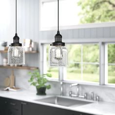 two lights hanging over a kitchen sink next to a window