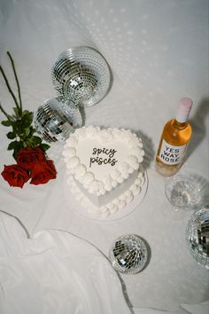 a heart shaped cake sitting on top of a table next to wine glasses and roses