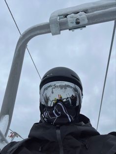 a person wearing a helmet and goggles while riding a ski lift in the snow