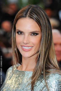 a woman with long brown hair and blue eyes smiles in front of the camera at an event