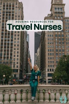 a woman in scrubs standing on the edge of a fountain with buildings behind her