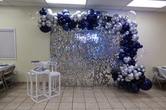 a room decorated with balloons and streamers in blue and silver colors for a birthday party