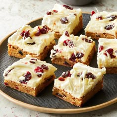 several pieces of cake on a plate with white frosting and cranberry toppings