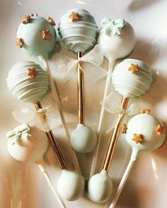 there are many white and green cake pops on the stick together with gold stars around them