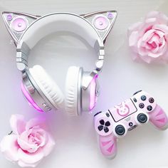 two video game controllers with cat ears and pink roses next to them on a white surface