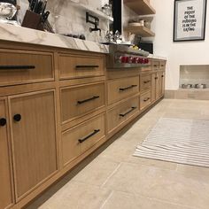 a large kitchen with wooden cabinets and marble counter tops on the floor, along with a rug