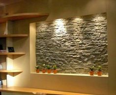 a stone wall in the corner of a room with shelves on either side and potted plants next to it