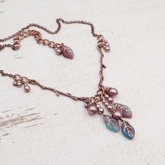 "This handmade necklace features beautifully detailed antiqued copper branches paired with clusters of limited-edition artisan Czech glass leaf beads. Each bead is a swirly mix of transparent purple, transparent teal, and opaque aqua blue glass with a metallic copper wash in the veins of the beads. I finished the clusters with metallic Czech glass faux pearl beads. --------------------------------------------------------------------------------------------- Dimensions and details: - The drop of Cheap Elegant Czech Glass Necklaces, Cheap Czech Glass Necklaces With Polished Beads, Luxury Czech Glass Necklaces For Gifts, Cheap Handmade Czech Glass Beaded Necklaces, Cheap Handmade Czech Glass Necklaces, Luxury Elegant Czech Glass Necklaces, Cheap Adjustable Czech Glass Necklaces, Luxury Elegant Necklace With Czech Glass, Luxury Czech Glass Beaded Necklace