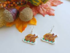 a pair of earrings sitting on top of a table next to autumn leaves and acorns