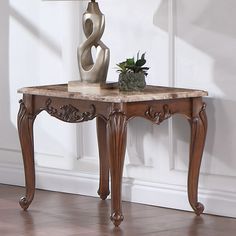 a table with a lamp on top of it in front of a white wall and wooden floor