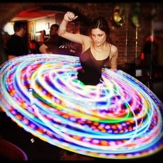 a woman standing in front of a hula hoop with colorful lights on the floor