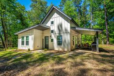 a small white house in the woods with trees and grass on the ground around it