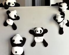 stuffed pandas hanging on the side of a refrigerator freezer with magnets attached to them