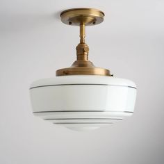 a light fixture hanging from the ceiling in a white and gold colored room with grey walls