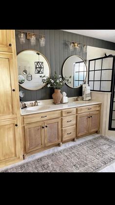 a bathroom with double sinks and two mirrors on the wall next to a rug in front of it