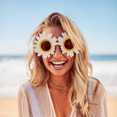 a woman with sunflowers on her eyes and sunglasses over her eyes at the beach