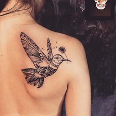 the back of a woman's shoulder with a bird and dandelion tattoo