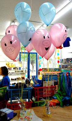 several balloons with faces on them hanging from the ceiling in a room filled with children's toys