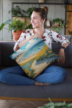 a woman sitting on a couch holding a pillow with an image of trees and mountains