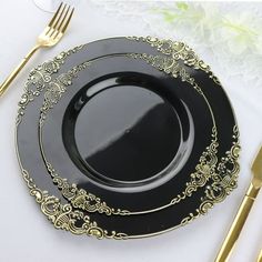 a black and gold plate with golden trimmings sits on a white tablecloth