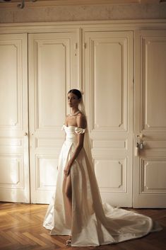 a woman in a wedding dress standing on a wooden floor next to white closets