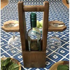 there is a wine bottle holder on the table with glasses and other items in it