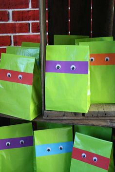 green bags with teenaged ninja turtles painted on them are sitting in front of a red brick wall