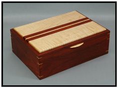 a small wooden box with a lid and two strips of wood in the top, on a gray background