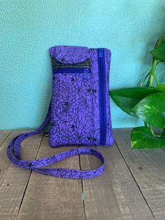 a purple purse sitting on top of a wooden floor next to a plant and blue wall