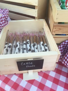 a wooden box filled with lots of brown and white cigars on top of a red checkered table cloth