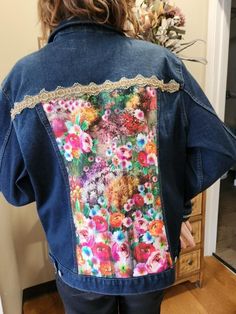 a woman wearing a jean jacket with flowers on it