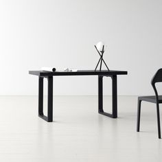 a black table with two chairs next to it on a hard wood floor in front of a white wall