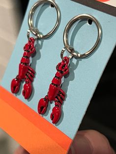 a pair of red lobster shaped earrings on a card