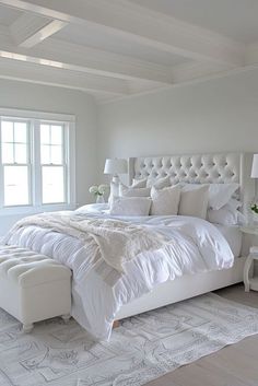 a large white bed sitting in a bedroom next to a window