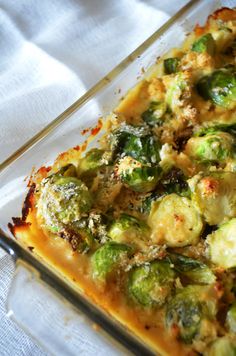 a casserole dish with broccoli and cheese in it on a white cloth