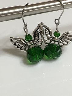 "Small angel earrings 1.25\" From hook to bottom, it dangle 1\" long, 8x10mm emerald green faceted crystal glass silver metals wings nickel and lead free, stainless steel fish hook Hand made jewelry. All purchase will arrive in gifts boxes. Thanks for stopping by!" Nickel-free Green Crystal Jewelry, Green Dangle Crystal Earrings, Green Crystal Earrings For Jewelry Making, Nickel-free Green Drop Crystal Earrings, Nickel-free Green Sterling Silver Crystal Earrings, Nickel-free Green Crystal Earrings In Sterling Silver, Silver Crystal Earrings For May Birthstone Gift, Gifts Boxes, Small Angel