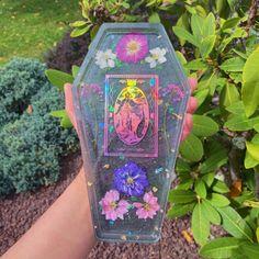 a person holding up a clear case with flowers on it and an animal in the center