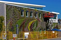 a large building with plants growing on it's side and a red truck parked in front of it