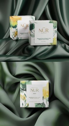 two boxes of nur soap sitting on top of a green satin background with flowers