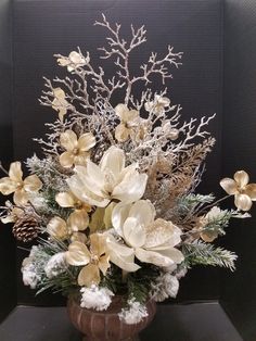 a vase filled with lots of white flowers on top of a wooden table next to a black wall