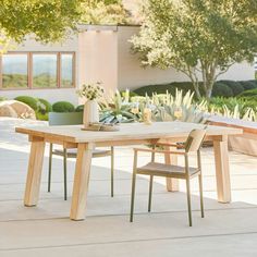 a wooden table with two chairs and a potted plant on the outside patio area