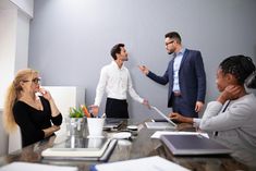 a group of people sitting around a table talking to each other in an office setting