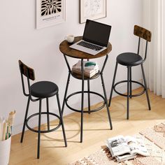 a laptop computer sitting on top of a wooden table next to two chairs and a rug