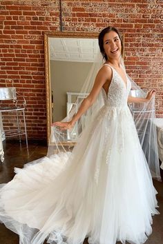 a woman standing in front of a mirror wearing a white wedding dress with sheer tulle