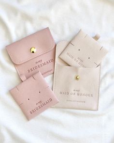 three bridesmaid cards are laying on a white sheet and one has a gold button